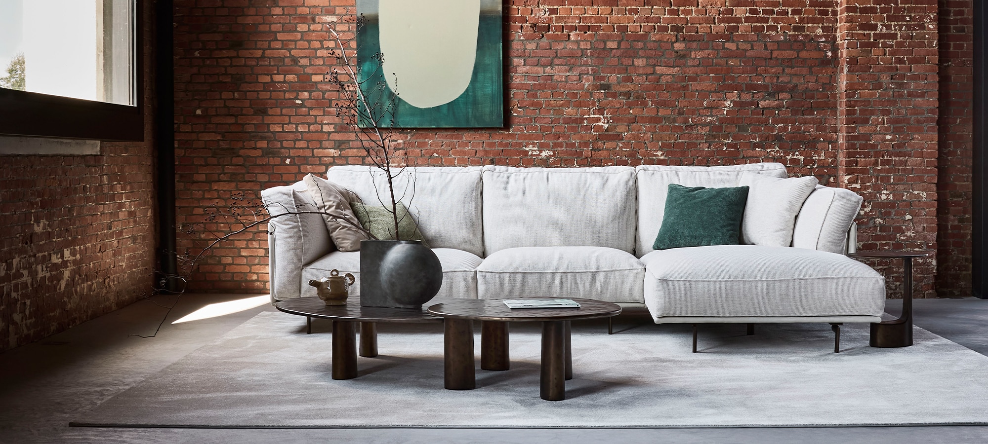 Linteloo Capri sofa and Charles coffee tables / Linteloo Capri bank en Charles salontafels in an industrial space with concrete and exposed brick / in een industriële ruimte met beton en baksteen