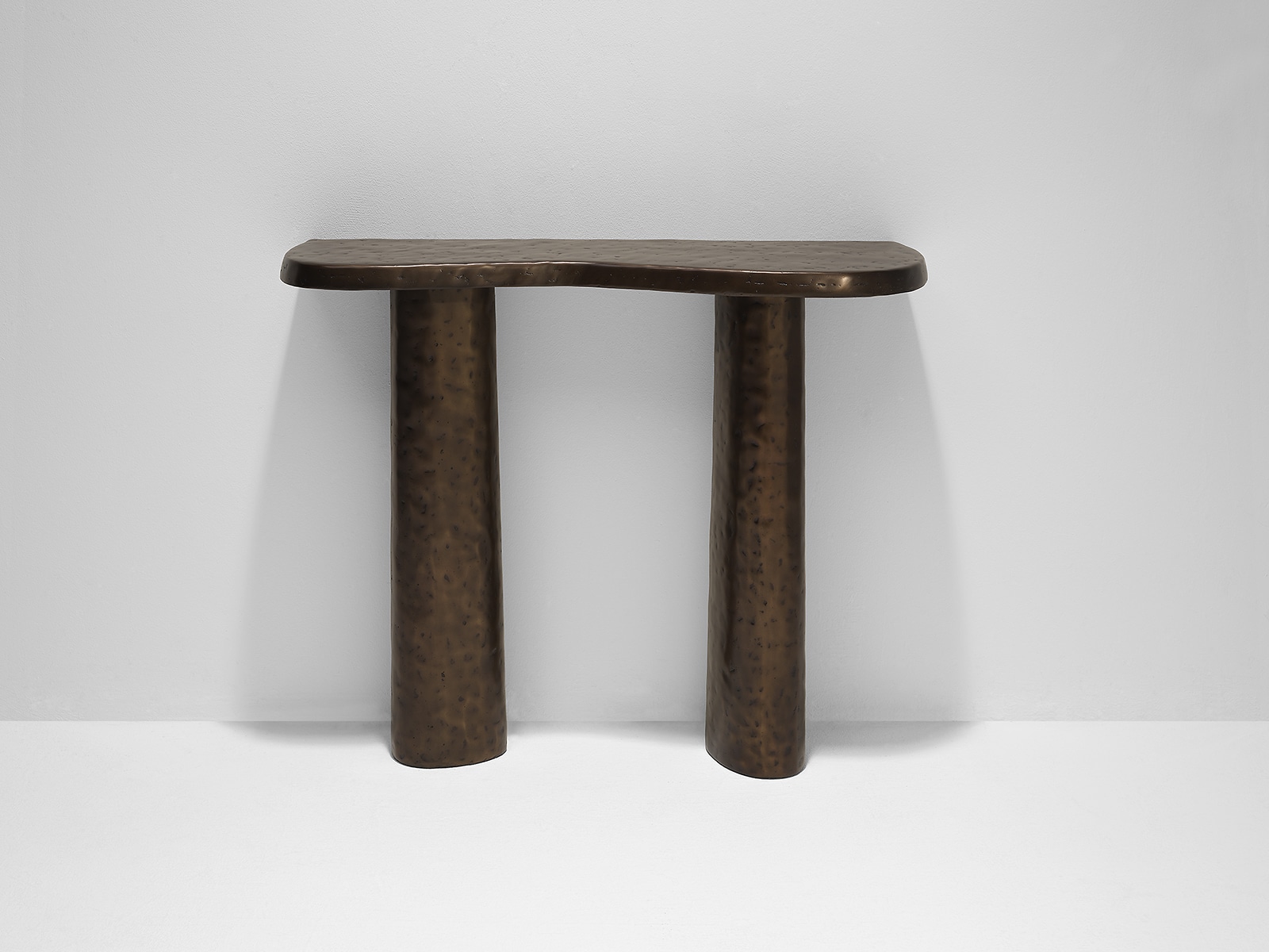 Ambient image of the Linteloo Charles console table made of cast aluminum with a bronze finish. The table top has an organic shape.