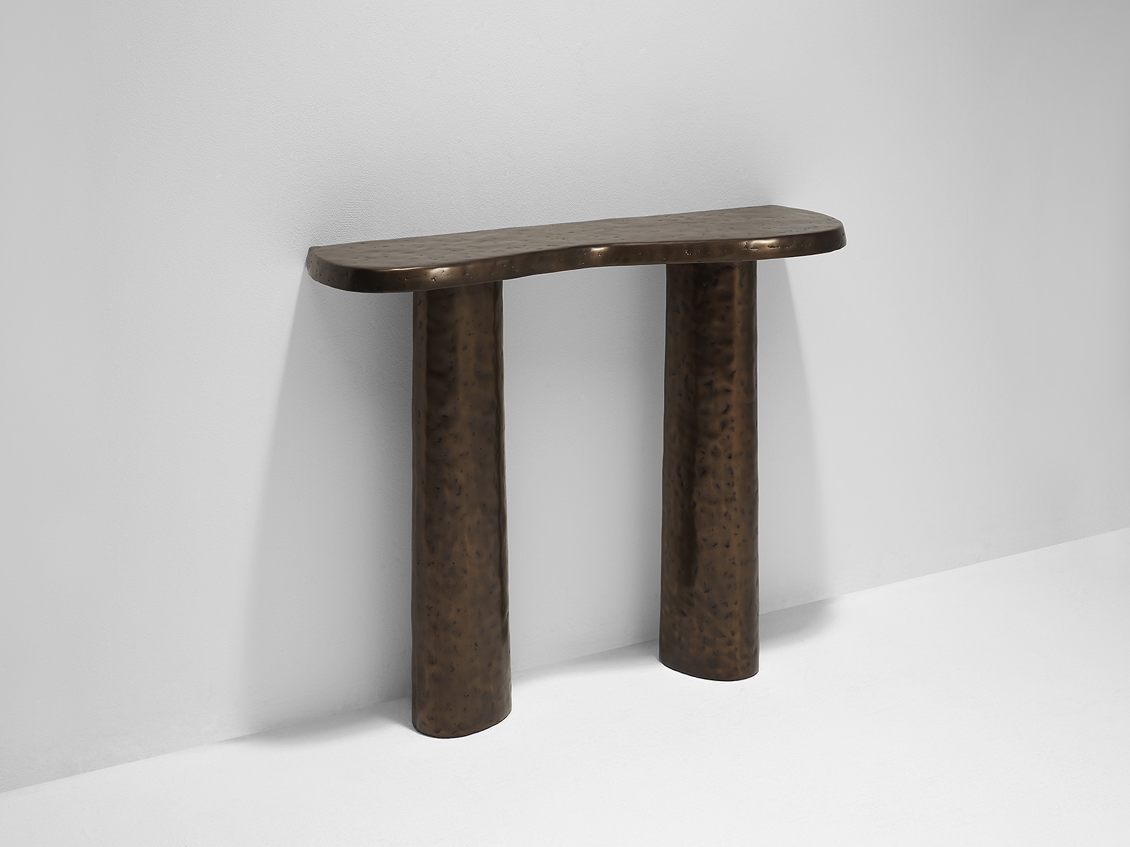 Ambient image of the Linteloo Charles console table made of cast aluminum with a bronze finish. The table top has an organic shape.