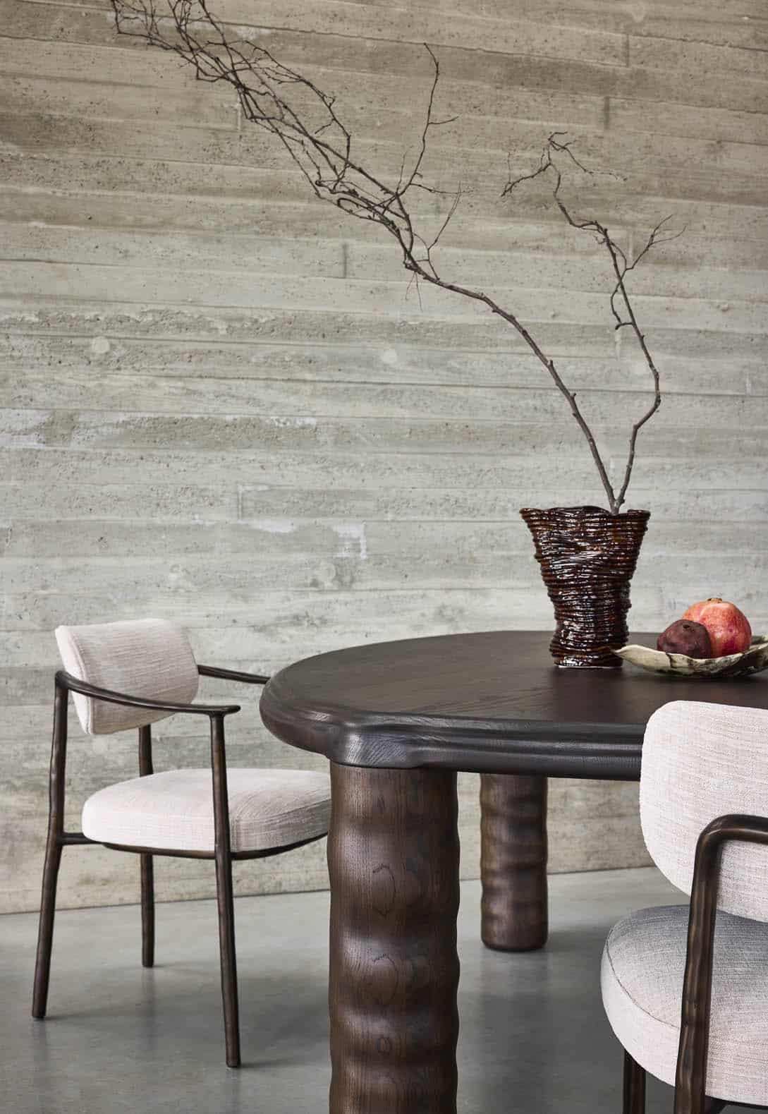 Linteloo dark oak wood Tembo dining table and bronze Gentle dining chairs in a concrete dining room.